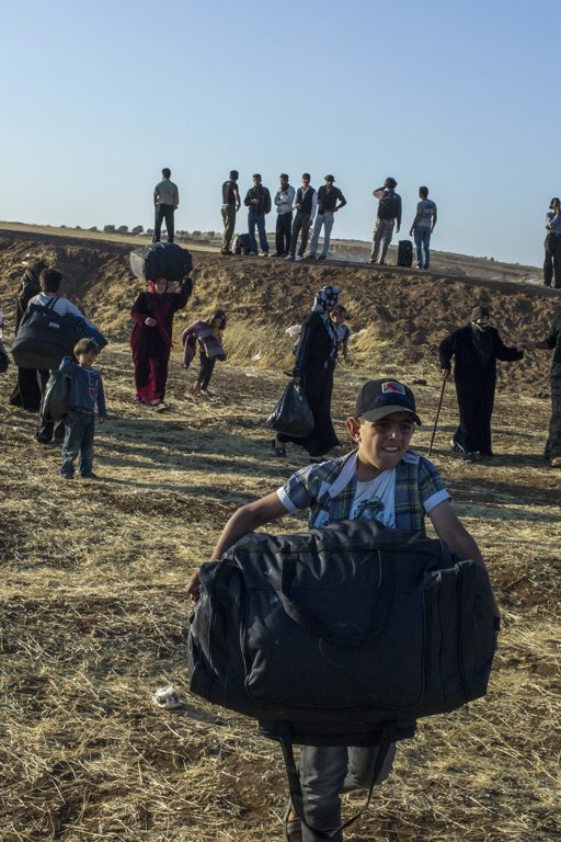 En pojke bär en väska när han flyr från Syrien.