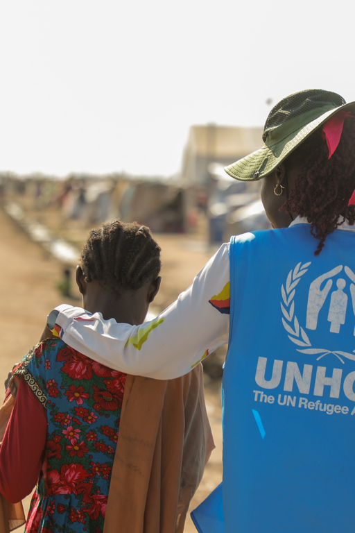 En UNHCR-medarbetare hjälper ett barn vid gränsen till Sudan.