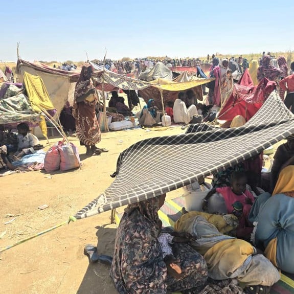 Människor som flytt kriget i Sudan sitter utspridda på marken.