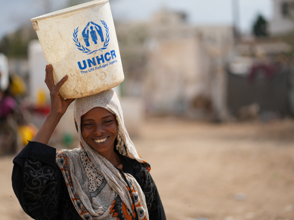 En kvinna på flykt i Jemen bär nödhjälp från UNHCR. Foto: UNHCR/Dotnotion