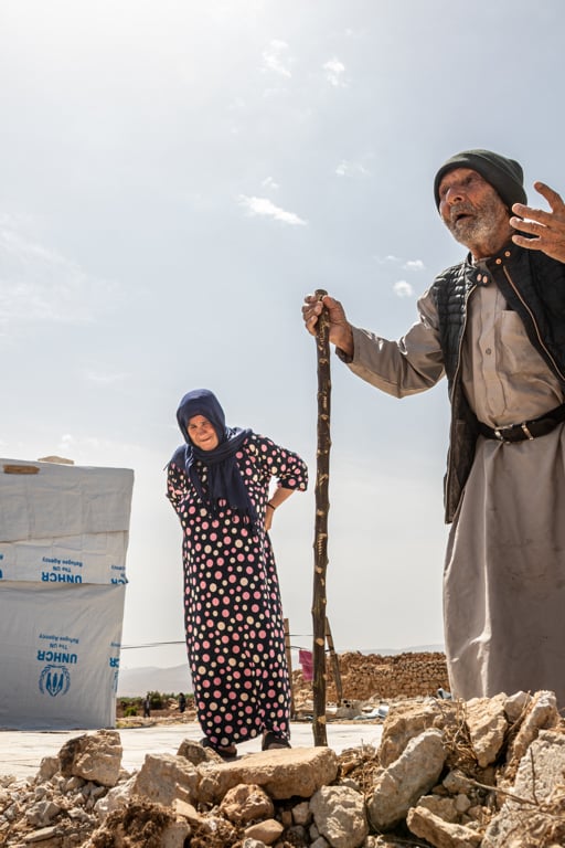 En äldre man och kvinna står utanför ett tält i Syrien.