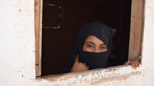 15-åriga Defa'a tittar ut ur ett fönster, hon och hennes familj är på flykt från sitt hem i Jemen.