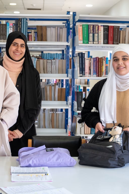 Tre kvinnliga studenter i Jordanien tittar mot kameran och ler.