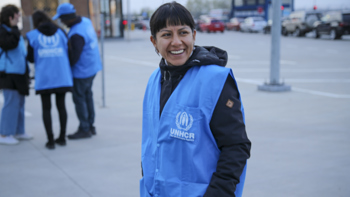 En kvinna med UNHCR-väst tittar in i kameran.