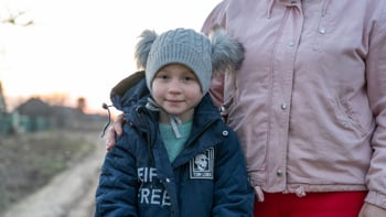 En flicka i Ukraina står med sin mamma på en väg.