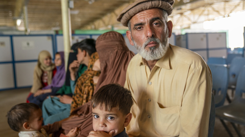 En afghansk man och hans son sitter på en bänk i ett mottagningscenter.