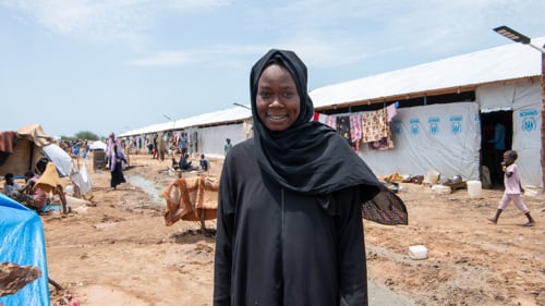 En kvinna står framför sitt RHU - Refugee Housing Unit.