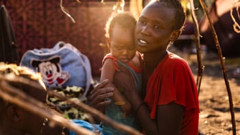 En kvinna från Sudan håller sin dotter i famnen i ett flyktingläger i Sydsudan.