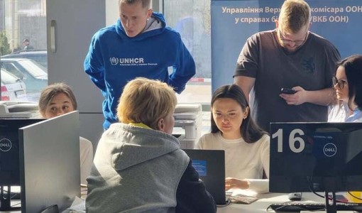 Kollegor i Ukraina hjälper en kvinna på flykt registrera sig för kontantstöd.