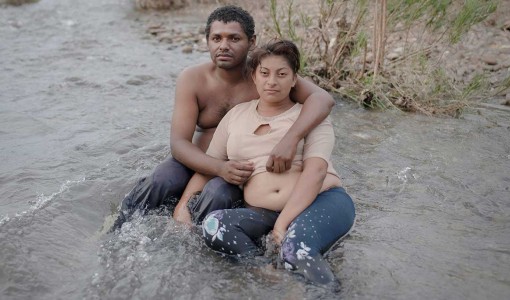 Santiago Niltepec, Mexiko. Christian och den höggravida Maritza sitter trötta och utmattade mitt i floden. Paret har vandrat i den stekheta solen hela dagen. Efter en lång dag svalkar de sina fötter i det kalla vattnet.