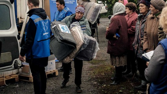 En kvinna i Ukraina får en filt från UNHCR.