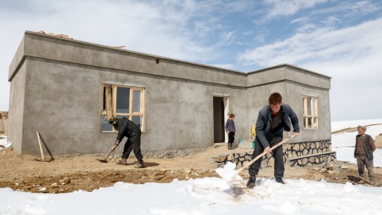 En familj skottar snö framför sitt hus